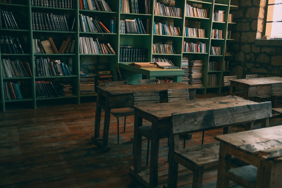 A rustic, vintage classroom featuring wooden desks and bookshelves filled with books.